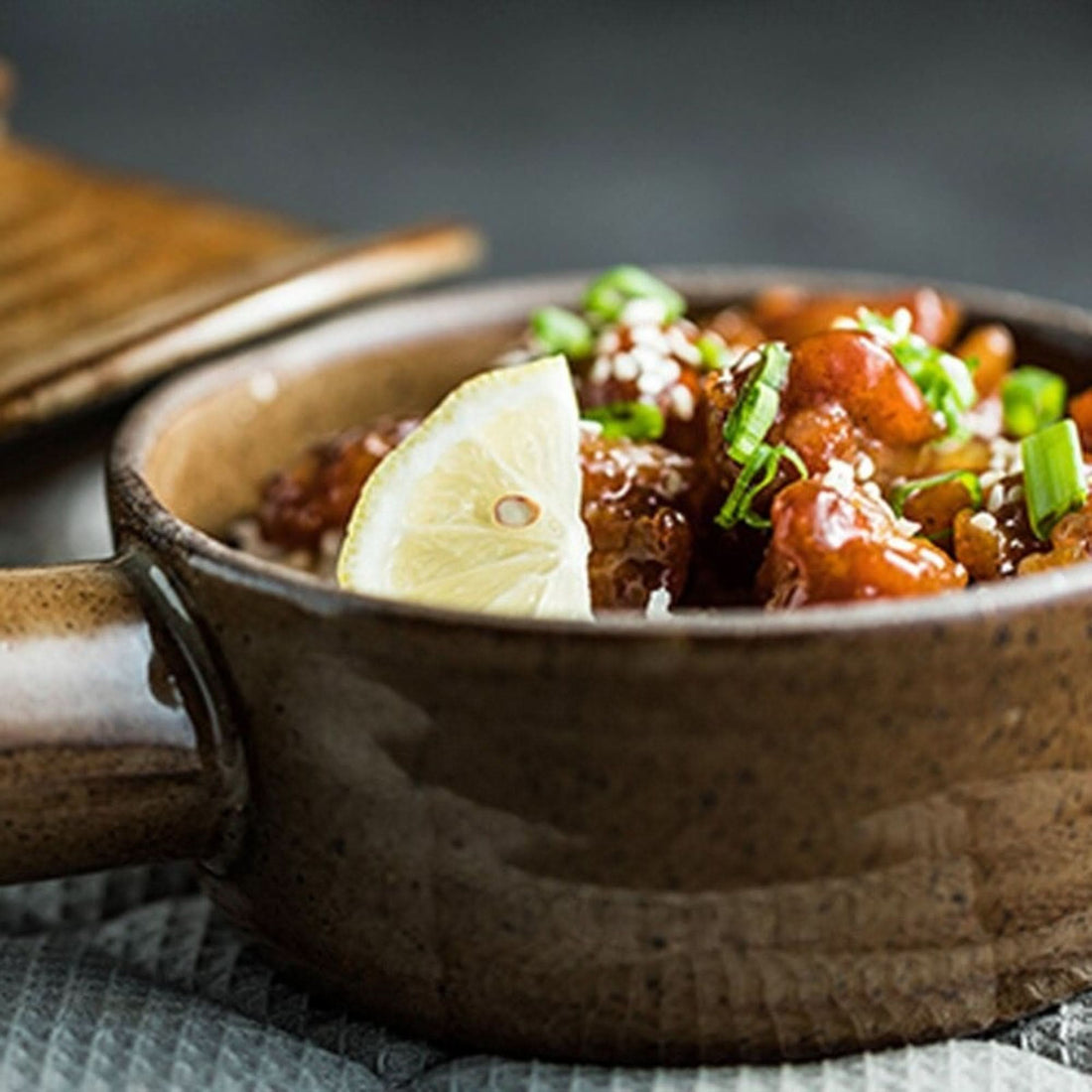 Rustic Nordic Stoneware Glazed Baking Plate holding glazed food with lemon slice and sesame seeds.