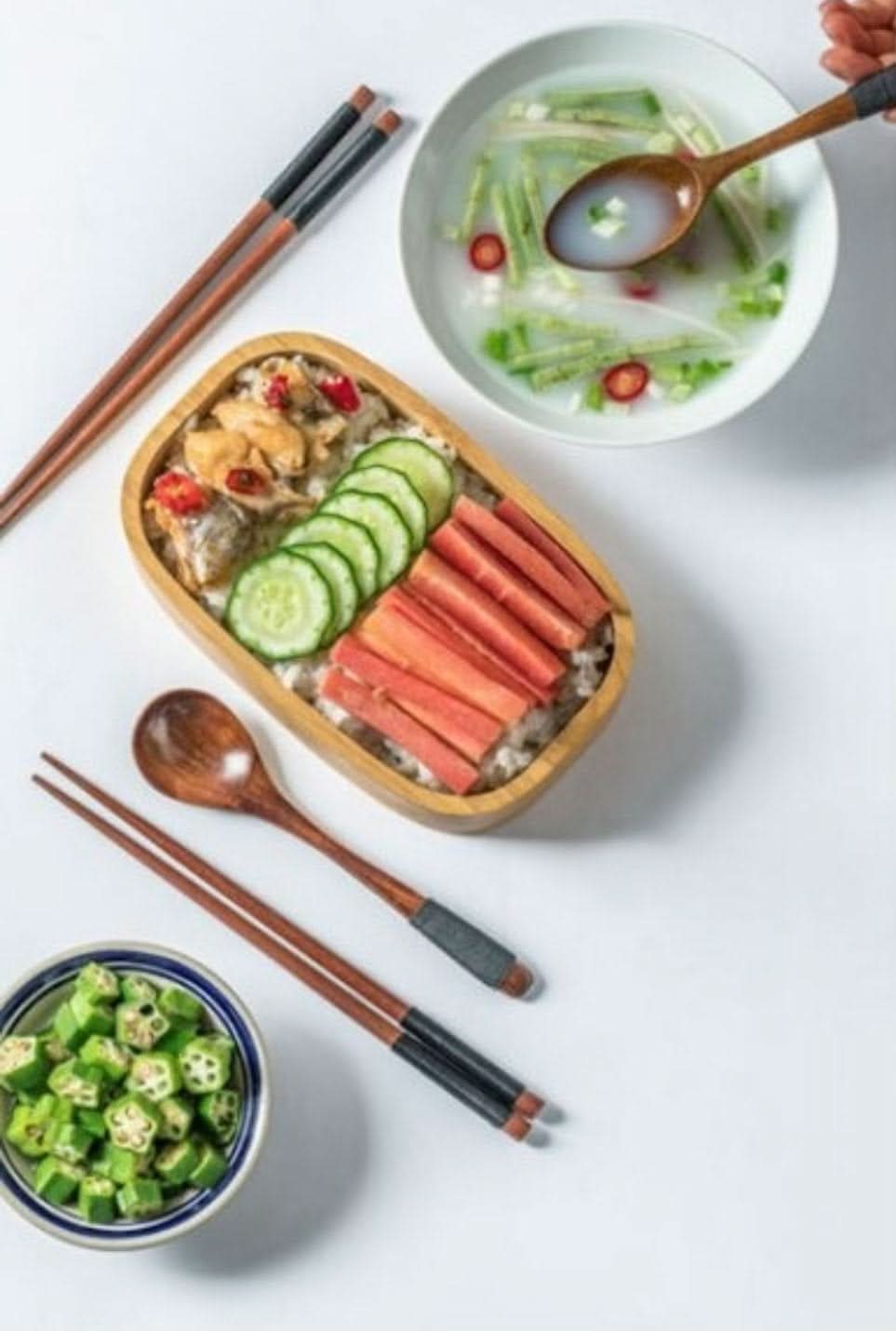 Natural wooden portable utensils with case, spoon, chopsticks, and chopstick rest, set for a meal.