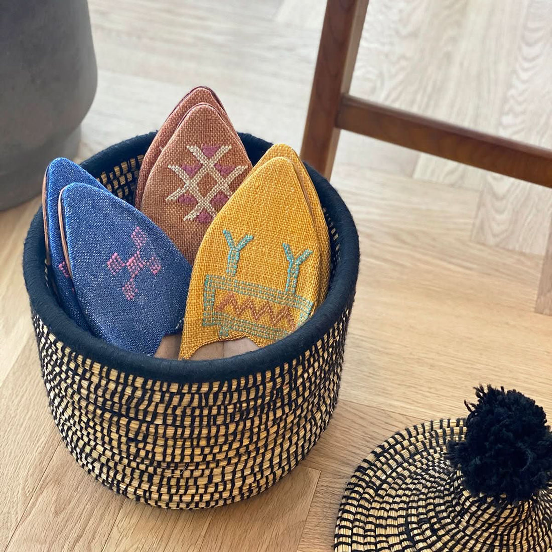 Raffia wool woven storage basket with colorful embroidered slippers.