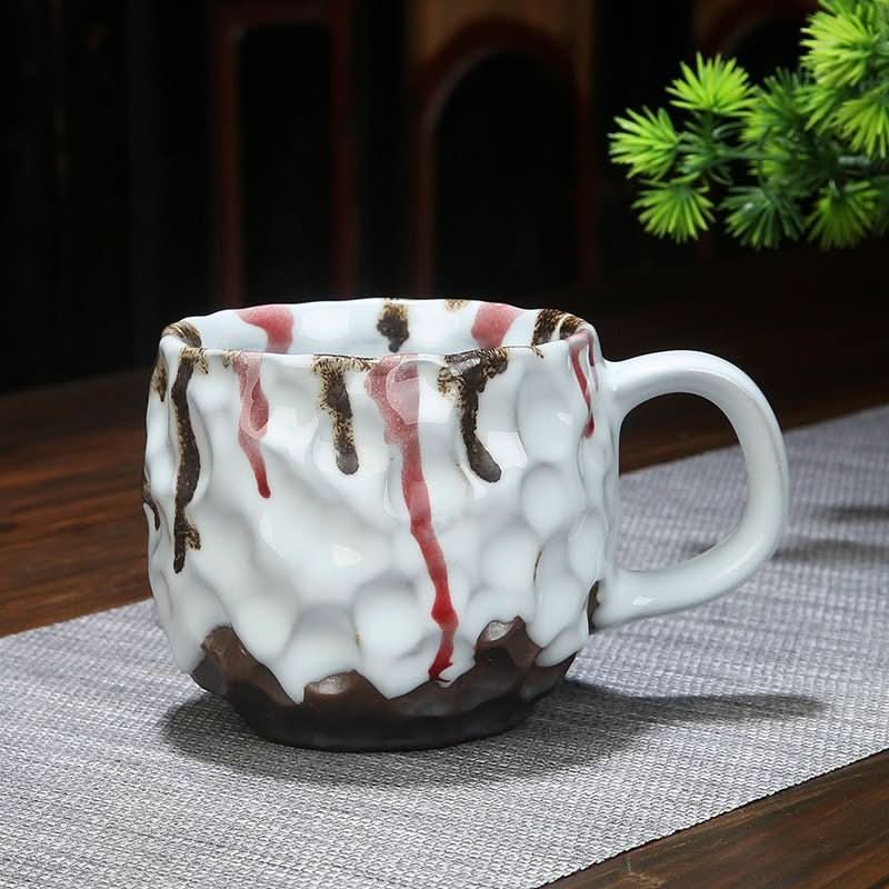 Retro handmade stoneware coffee cup with red and brown reactive glaze drips. Colorful pottery.