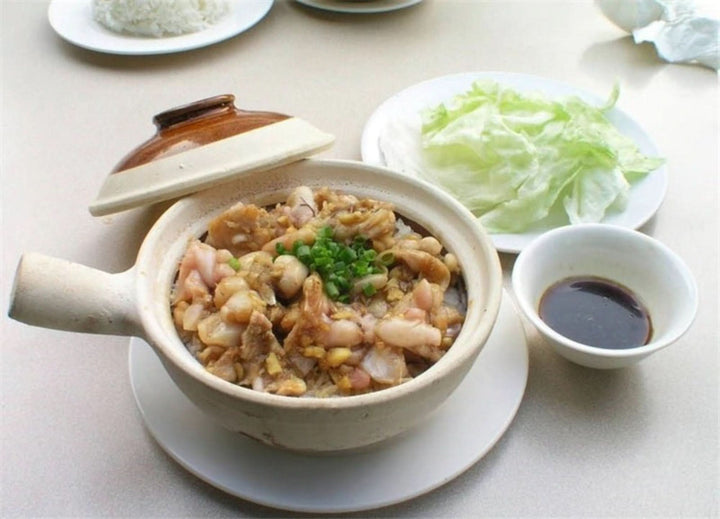 Rustic unglazed stoneware baking plate with Asian cuisine dish, white rice, and lettuce.