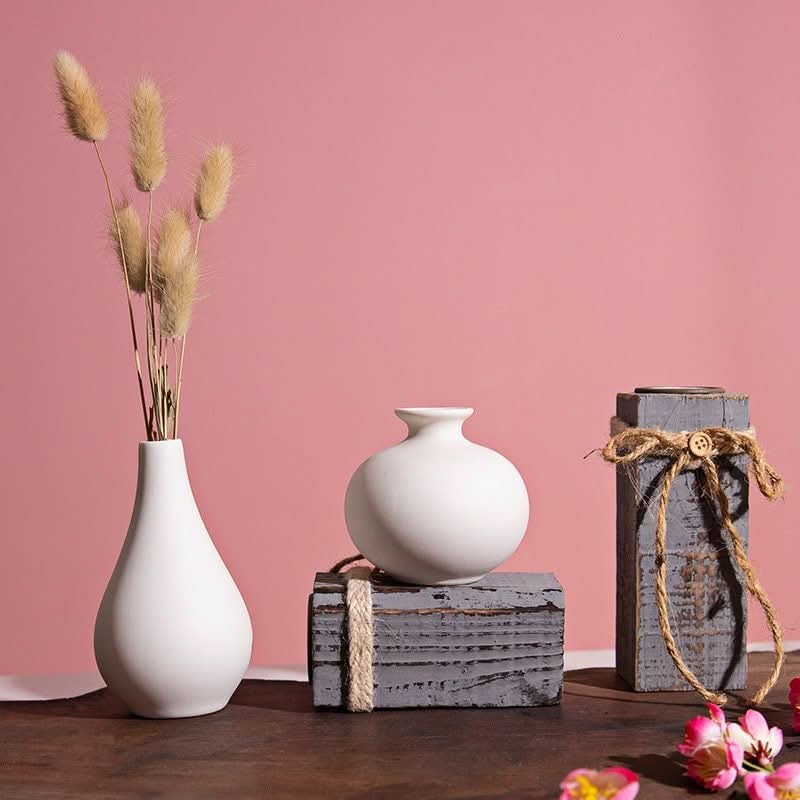 White ceramic bud vases with dried florals on rustic wood blocks, Nordic style table decor.