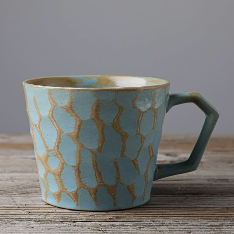 Stoneware coffee cup, vintage Japanese style mug with textured blue glaze, on wood surface.