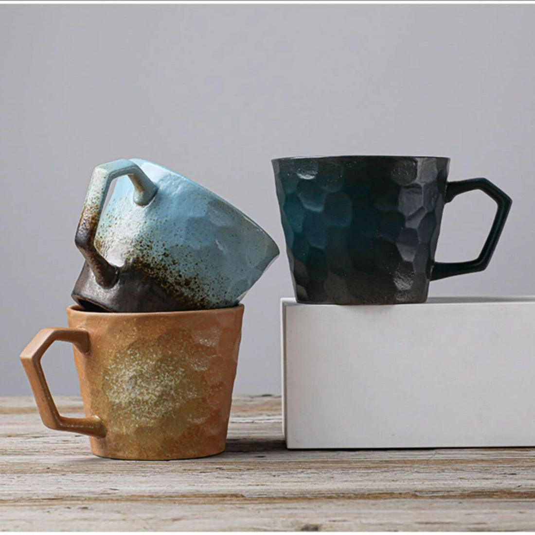 Vintage Japanese style stoneware coffee cups in brown, blue, and dark green hues.