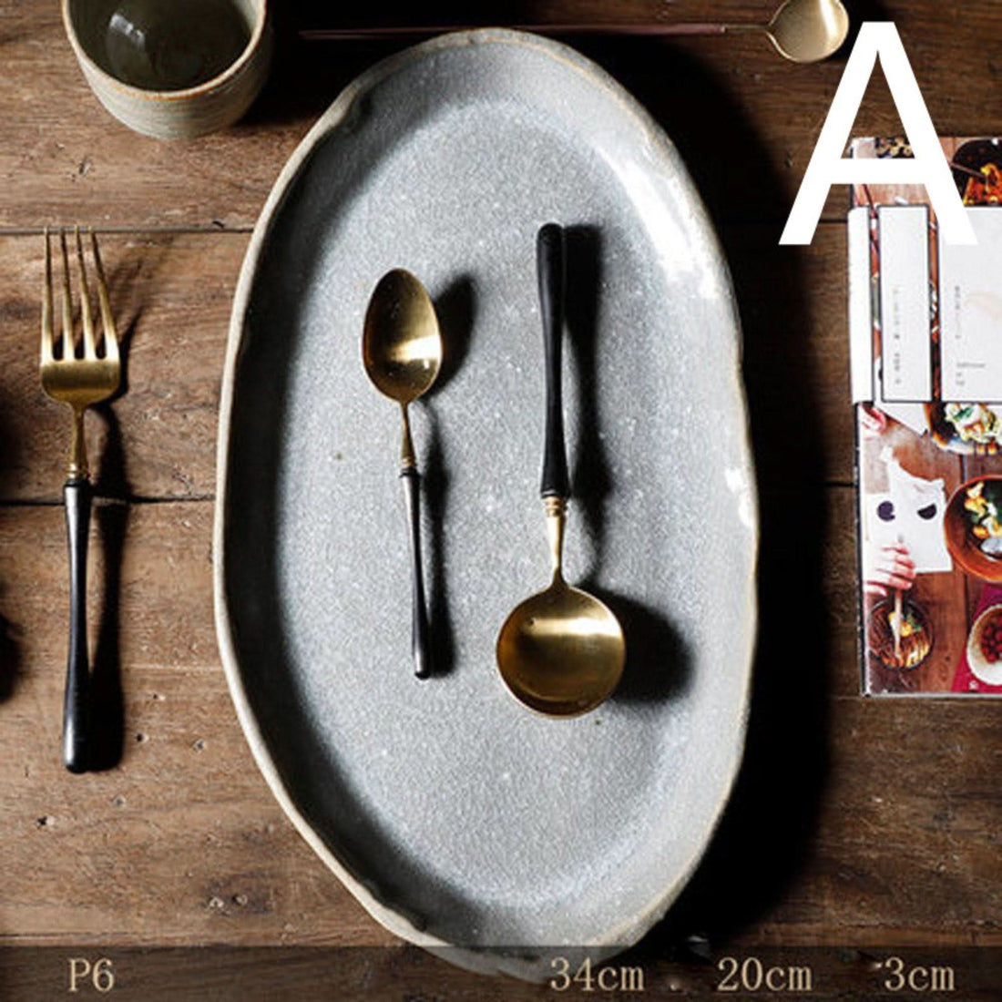 Stoneware Handmade Irregular Ice Cracked Ceramic Tableware, grey oval plate with gold & black spoons, fork on wood.