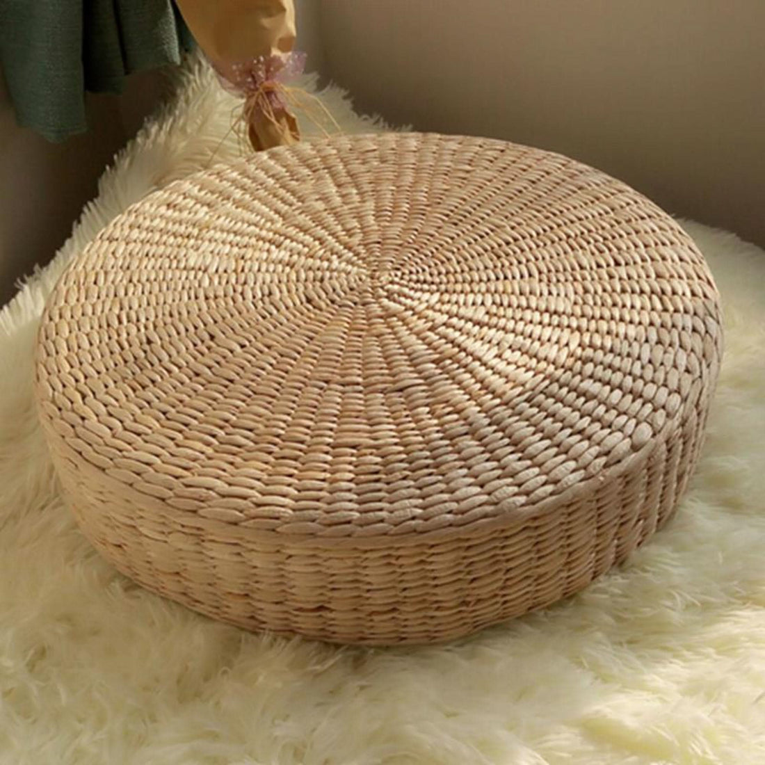 Natural straw floor pouf meditation cushion on plush white rug.
