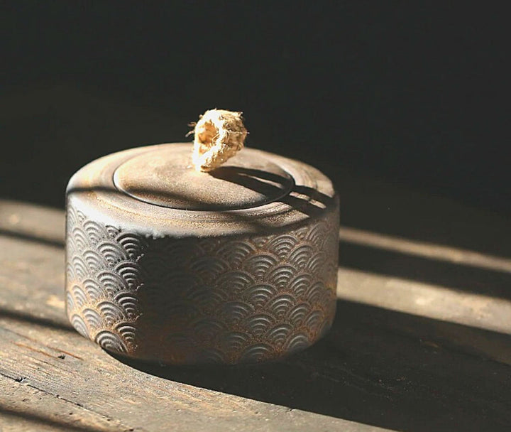 Vintage kitchen canister, black tea jar with Japanese wave pattern, rope handle, on rustic wood.