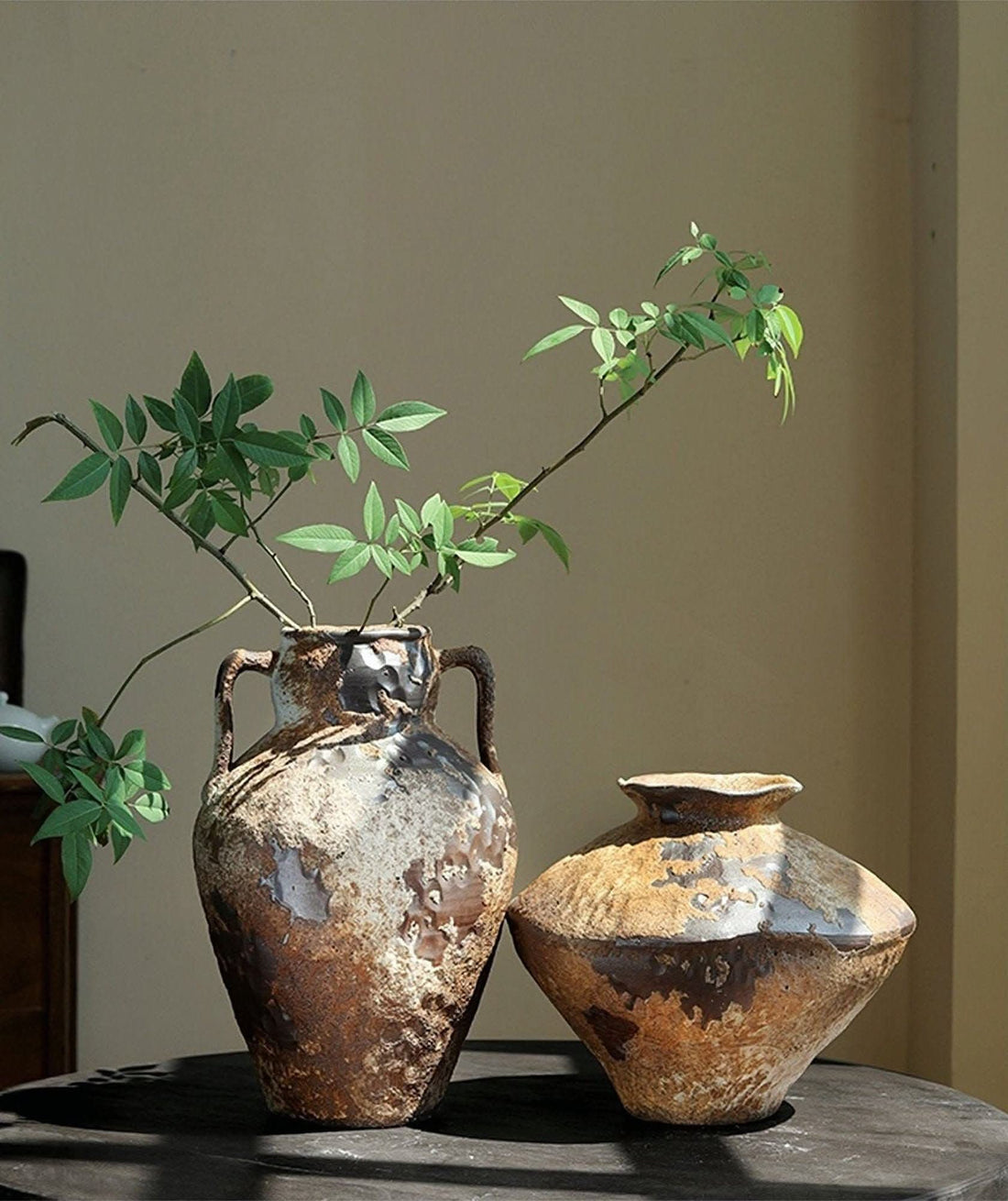 Wabi-Sabi Distressed Rustic Vases: Two distressed ceramic vases with natural green branches.