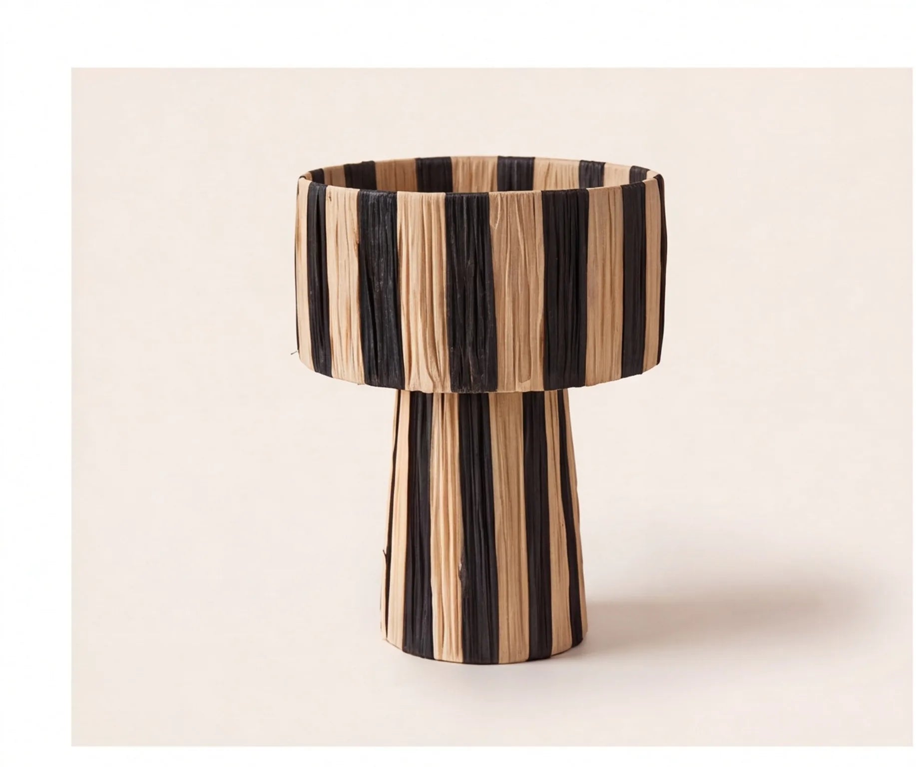 Moroccan raffia striped desk lamp with black and natural tan woven horizontal stripes on off-white background