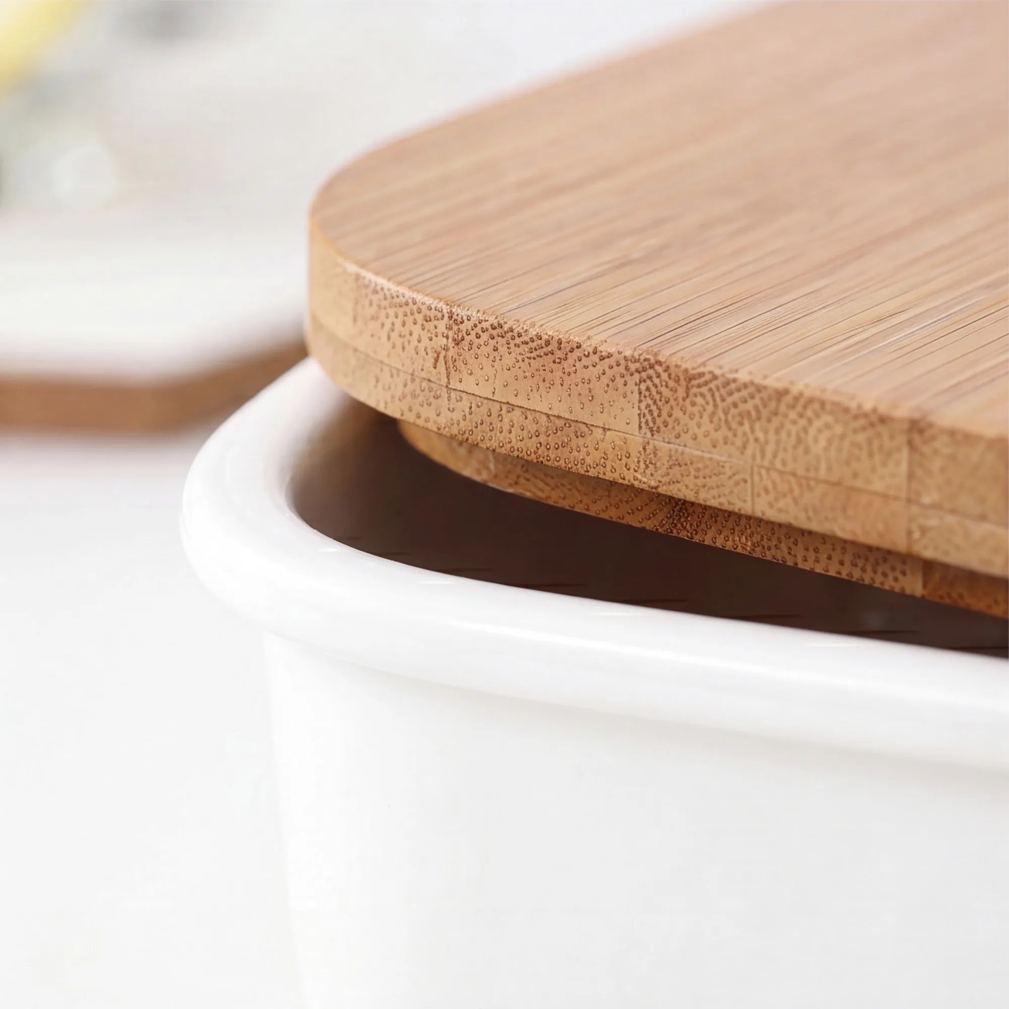 Close-up of white ceramic bento box rim meeting bamboo lid grain with lid lifted slightly