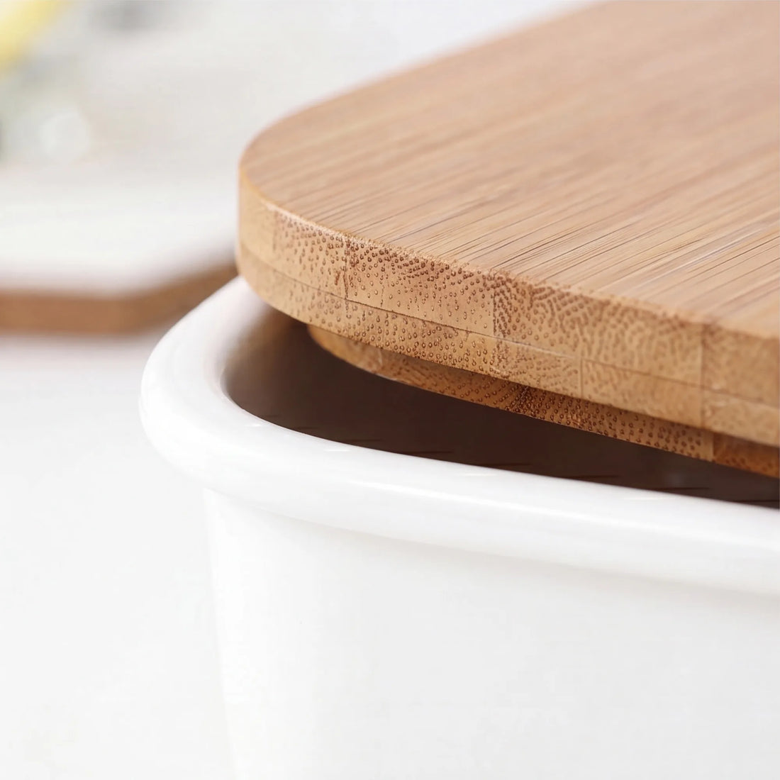 Close-up of white ceramic bento box rim meeting bamboo lid grain with lid lifted slightly