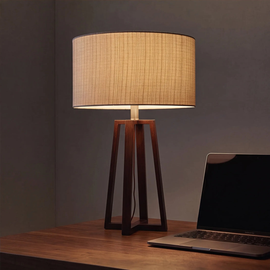 Walnut linen table lamp as sole light on desk at night with closed laptop, calm mood