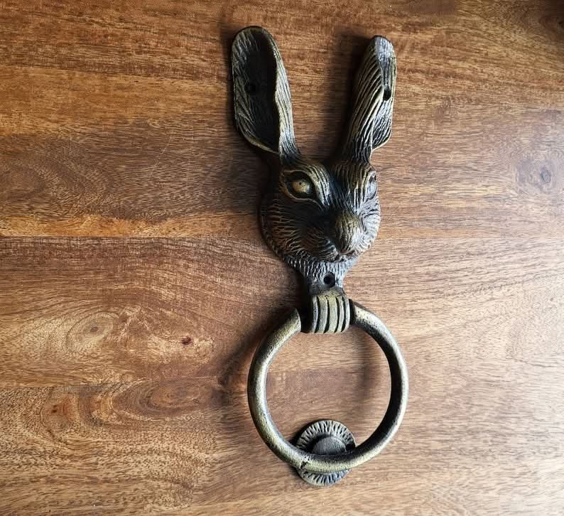 Antique brass rabbit door knocker on a wooden background. Home decor.