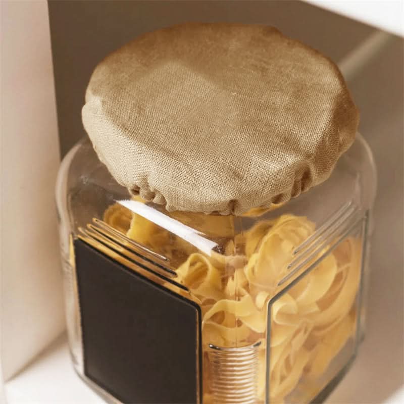 Natural linen bowl cover on glass jar filled with pasta. Home decor.