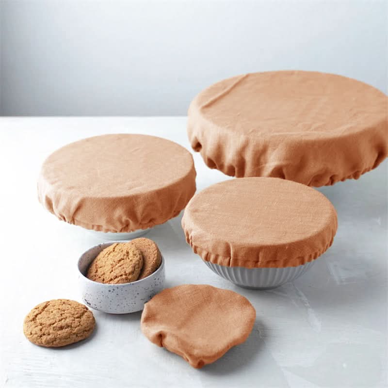 Set of peach linen bowl covers with cookies on a table.
