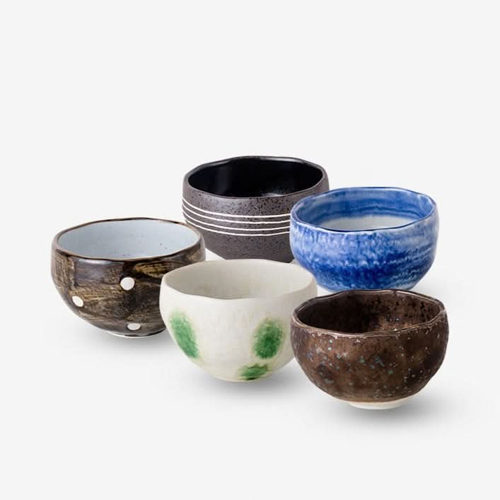 Assortment of ceramic Japanese tea set bowls in various colors and handcrafted textures.