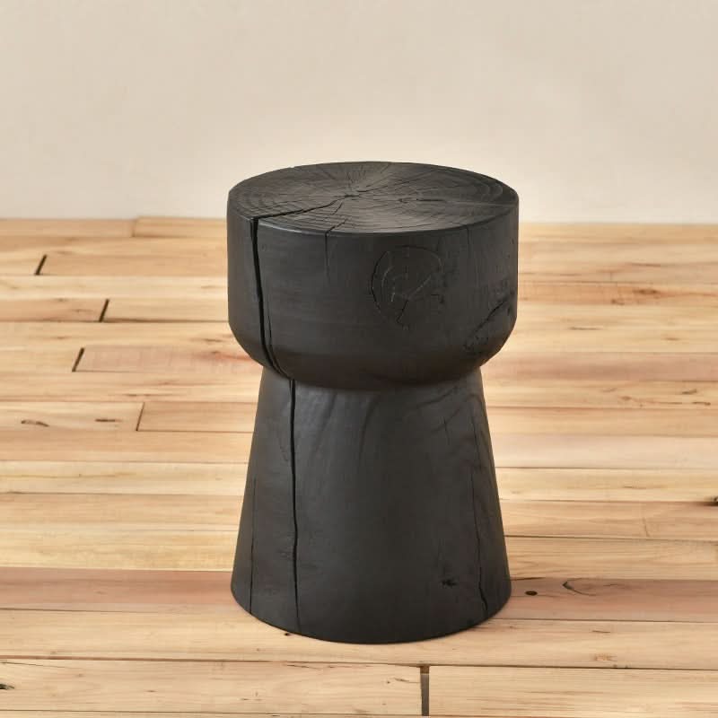 Black Wood Stool with rustic texture on a natural wood floor.