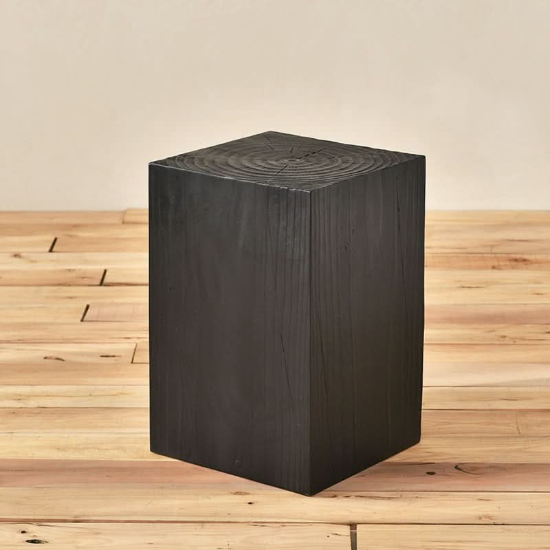 Black wood stool with visible grain, on a light wood floor.