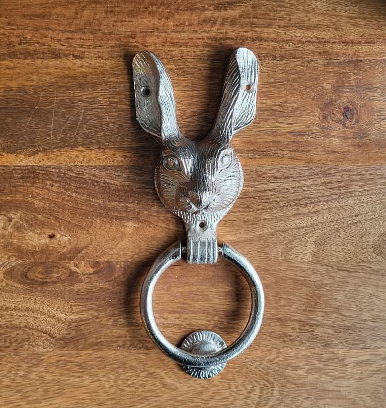 Silver brass rabbit door knocker on a wooden background.