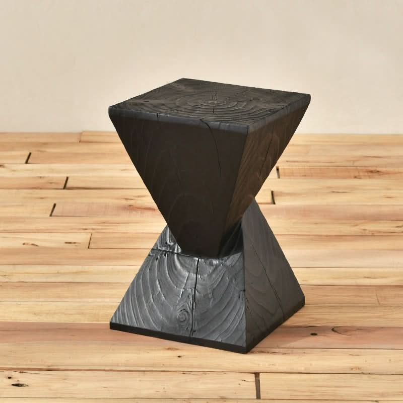 Black wood stool with textured finish on light wood floor.