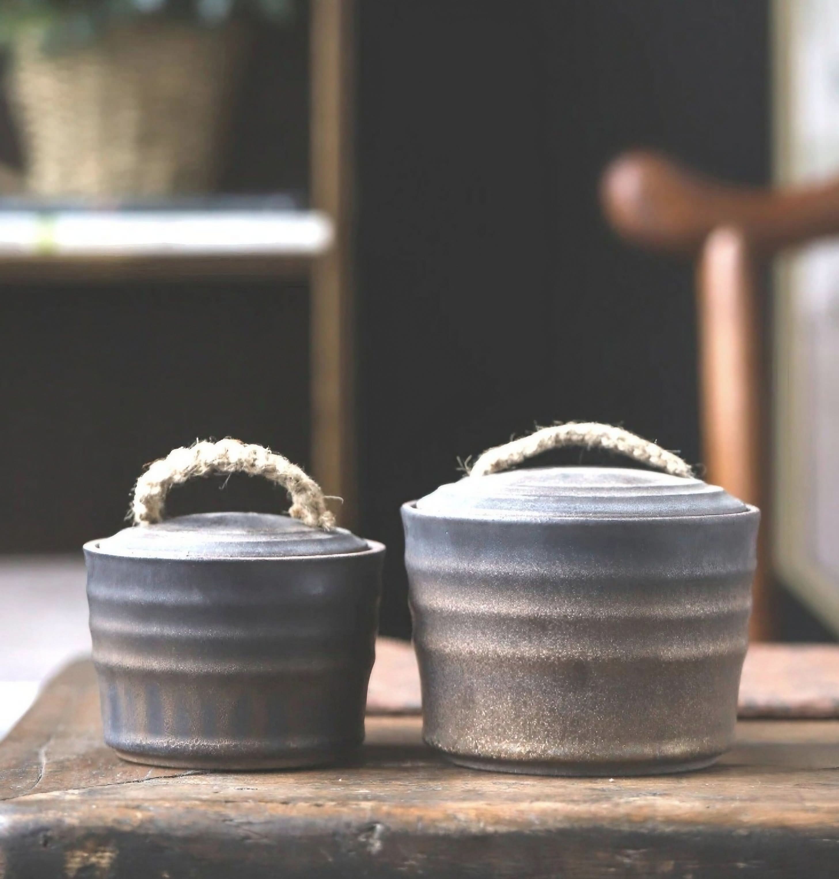 Wabi-Sabi ceramic storage jars with rope handles, two dark grey airtight lidded jars on wood.