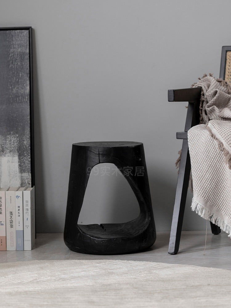 Black wooden stool, rustic design, unique shape.