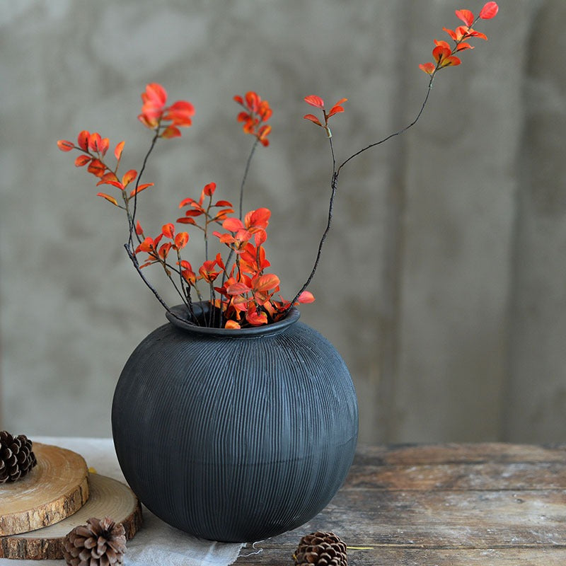 Black textured ceramic vase with orange flowers.