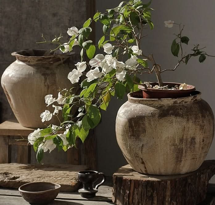 Rustic handmade ceramic vases with white blossoms, earthy tones, natural home decor.