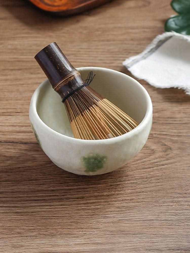 Japanese Mino-yaki wedge-shaped matcha bowl with bamboo whisk on wooden table