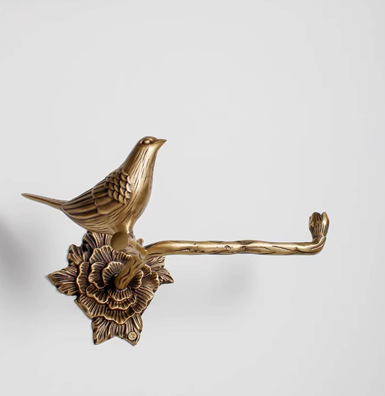 Antique brass bird toilet paper holder with floral base, part of a bathroom set.