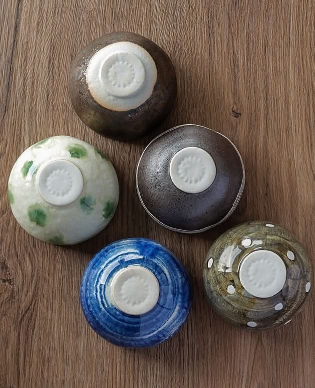 Japanese imported Mino-yaki wedge-shaped matcha bowls in various colors and glazes on wood.