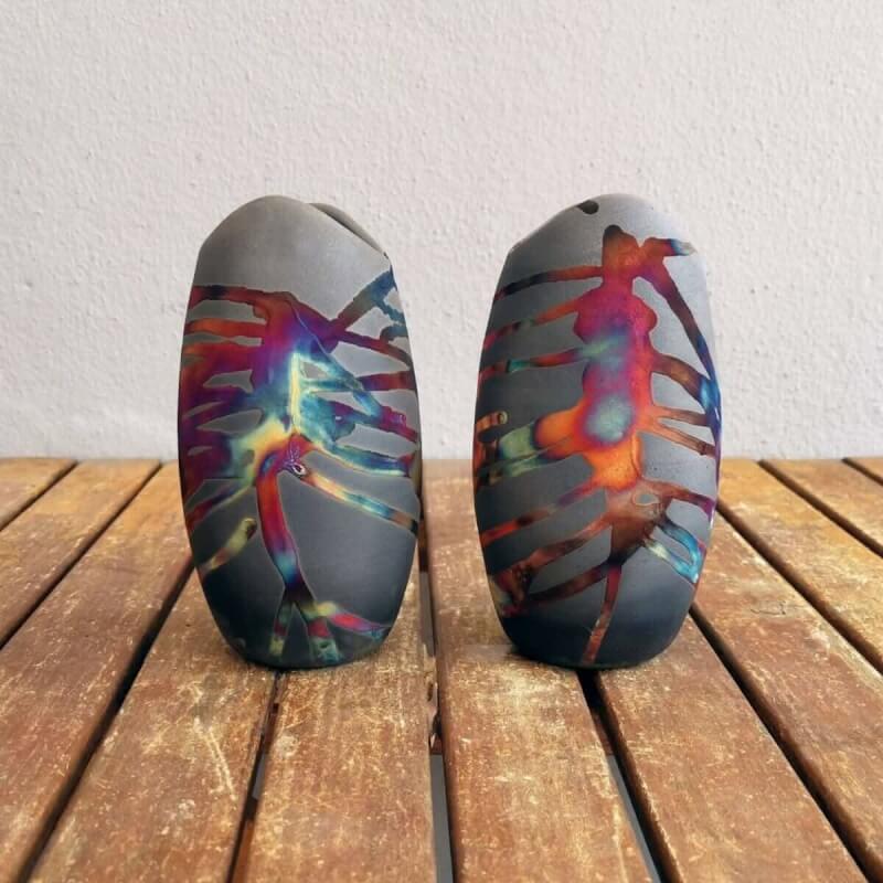 Two dark gray ceramic koi vases with colorful raku patterns.  Bottle-shaped with wavy mouths.