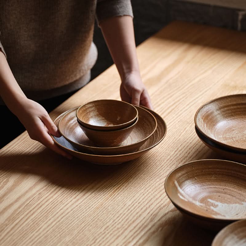 Brown clay tableware handmade set on a wooden table. Earthy tones, textured finish.