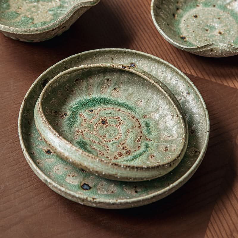 Artisan Green Dinnerware: Textured ceramic bowls and plates in speckled green and brown hues.