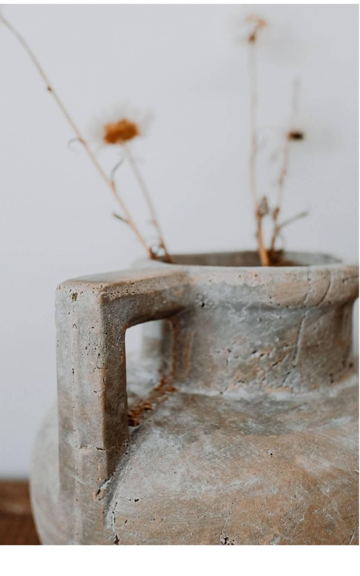 Antique style clay pot, raw earthenware with distressed texture, holding dried flowers.