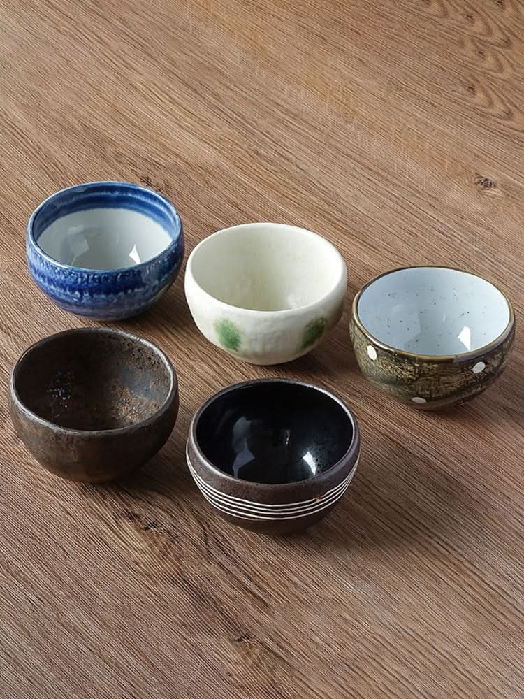 Japanese imported Mino-yaki wedge-shaped matcha bowls in assorted rustic glazes on wood grain table.
