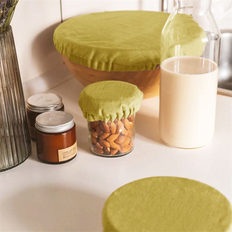 Olive green linen bowl covers shown on bowls and jars of almonds and milk.