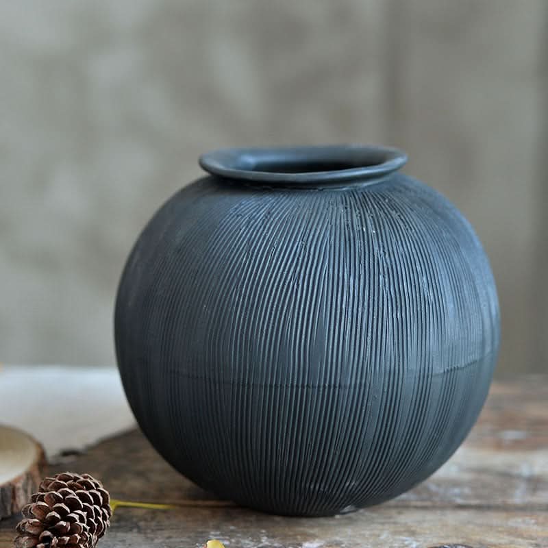 Textured black ceramic vase on a wooden surface, home decor accent.