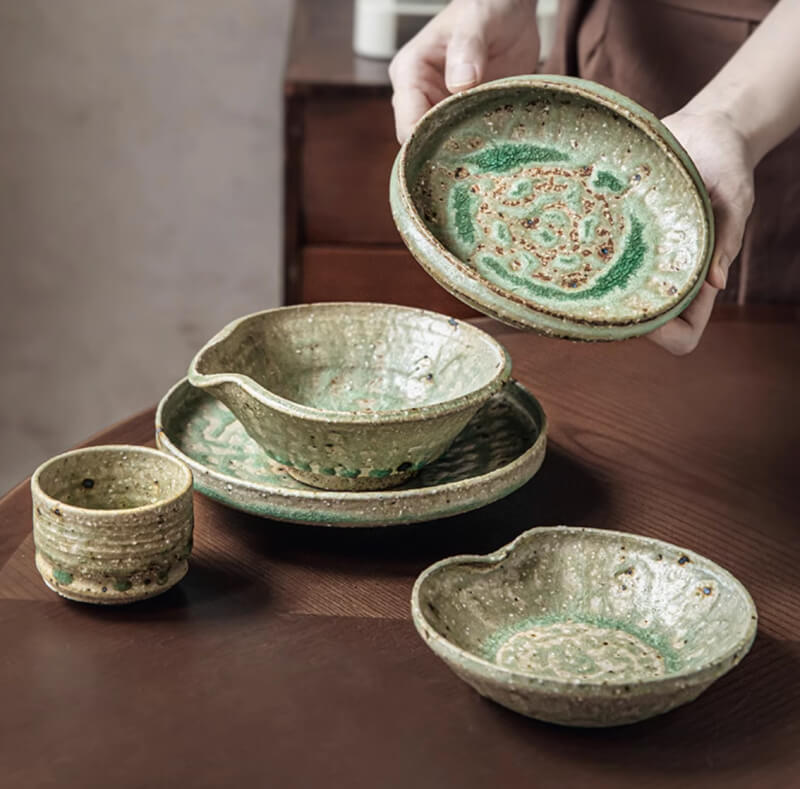 Artisan Green Dinnerware: Rustic ceramic bowls and plates with speckled green glaze.