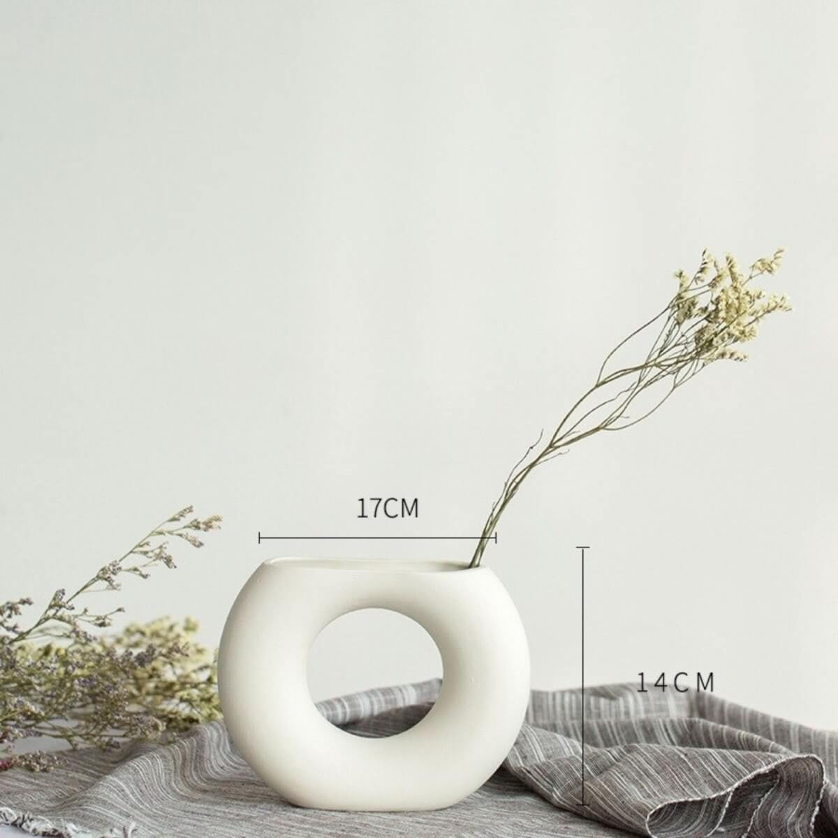 Abstract white flower vase, minimalist decorative vase with dried flowers on grey linen.