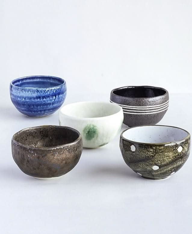 Five Japanese Mino-yaki wedge-shaped matcha bowls in various textures and colors.