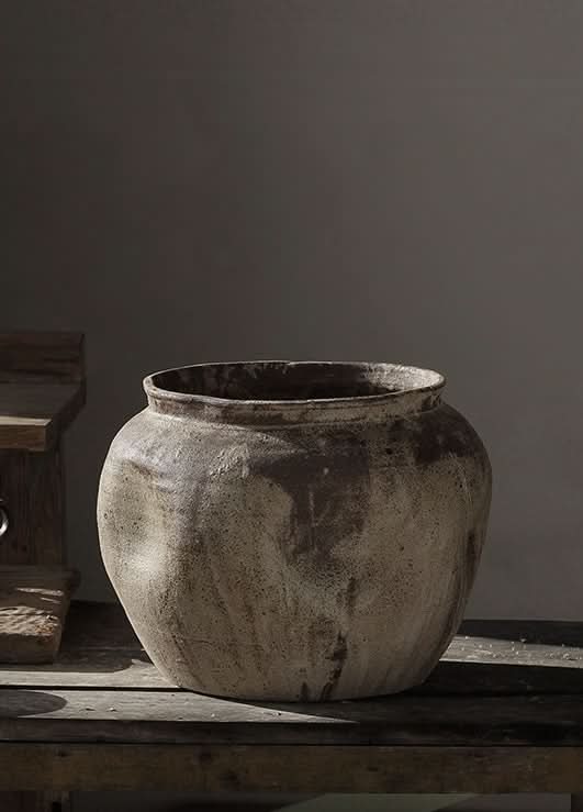 Rustic handmade ceramic vase in earth tones on a wooden surface, perfect for home decor.