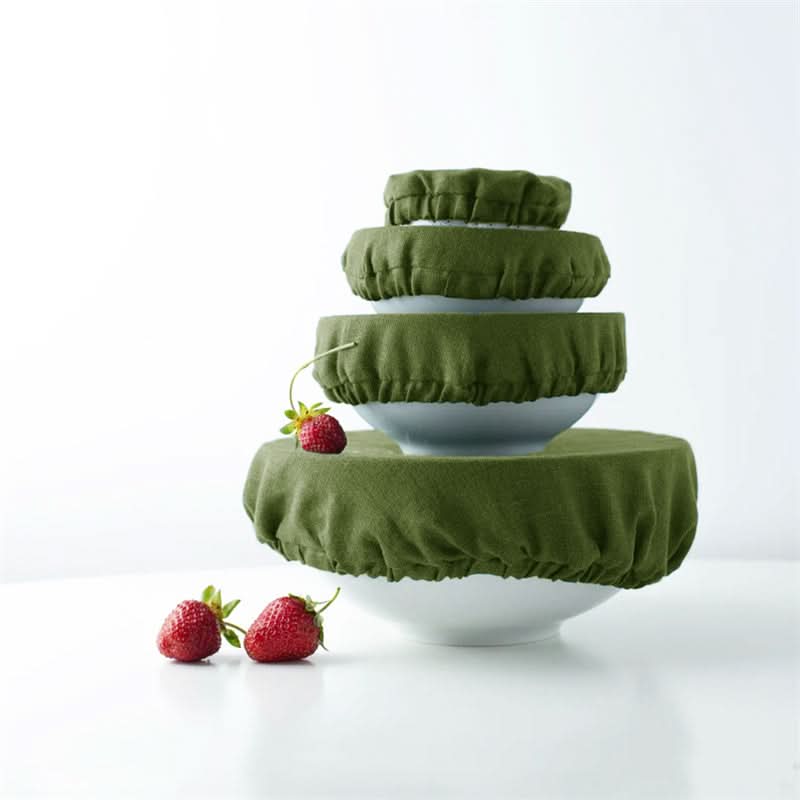 Set of olive green linen bowl covers on white bowls, with strawberries.