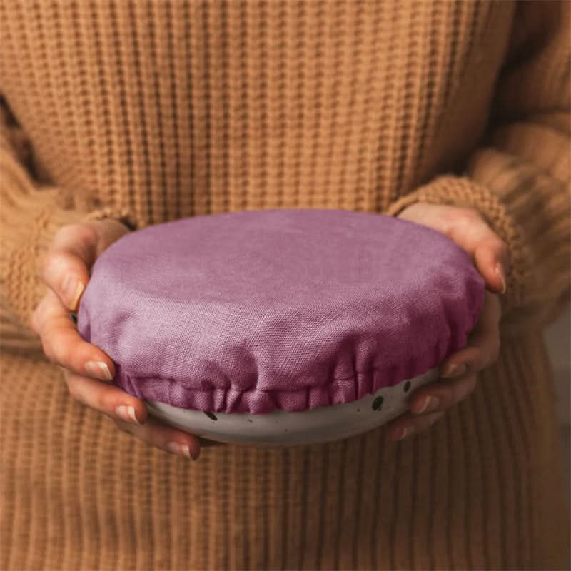 Plum linen bowl cover with elastic edge, hands holding ceramic bowl.