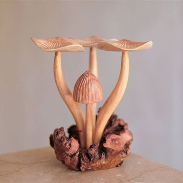 Hand-carved mushroom sculpture in natural wood, featuring delicate caps and a rustic base.