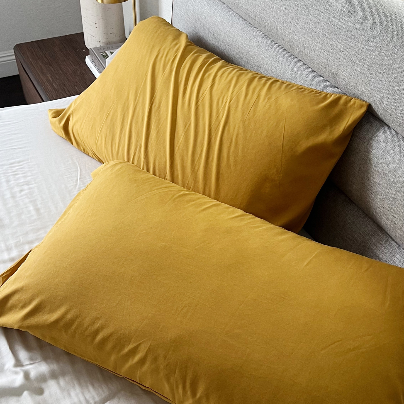 Golden yellow Copper Infused Bamboo Pillowcase Set on a bed with white sheets.