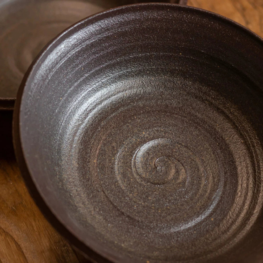 Overhead view into a deep, dark brown ceramic bowl showing swirling glaze patterns and texture.