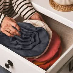 Hands fold colorful linen bowl covers in a drawer, a touch of home decor.