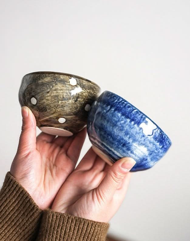 Mino-yaki wedge matcha bowls in brown polka dot and blue swirl glaze held by hands.