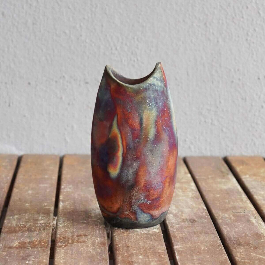 Two handmade raku pottery vases, vibrant multicolored, bottle-shaped.